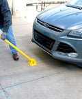 Person using Tough As Nails Ground Mount Heavy Duty Steel Fold Down Bollard to secure driveway near parked car.