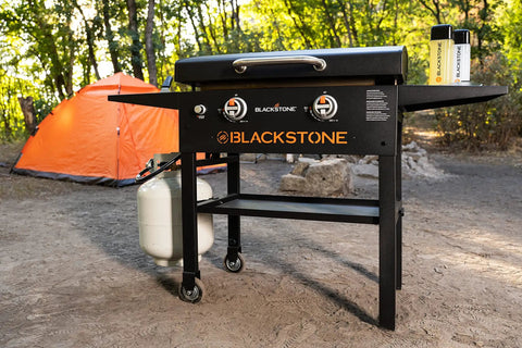28 Inch Griddle With Protective Hood And Counter Height Side Shelves In Powder Coated Steel For Outdoor Grilling, 524 Square Inches Of Cooking Space, Perfect For Feeding A Crowd shown in camping setting