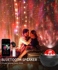 Cozy scene with couple experiencing 3 In 1 Night Light Projector With Bluetooth Speaker And Led Cloud in dark room with star effects.