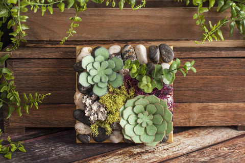 Decorative felt succulents with rocks on wood background, representing natural decor craft inspiration