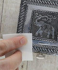 Using Shine Rite 2-Inch Polishing Pads For Jewelry to polish a metal box with an elephant design.
