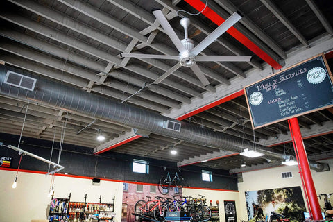 Top Shelf Modern Smart Ceiling Fan With Hella Fast Airflow And Slick WiFi App Control Featuring SenseMe Tech For Massive Rooms In Premium Brushed Aluminum Finish in a bike shop interior.