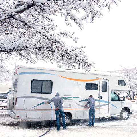 Two people using 12 Foot Heated Drinking Water Hose With Freeze Protection Down To Minus 40 Degrees on RV in snowy conditions