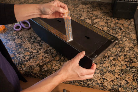Applying Ultra Strong Clear Double Sided Mounting Tape 1 Inch Wide By 60 Inches Long Weatherproof Adhesive on a flat surface.