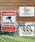 Warning sign for 24 hour video surveillance mounted on a fence with screws and zip ties shown as mounting options, nearby sports field visible.