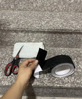 Hand holding Heavy Duty Anti Slip Tape 2 Inch Wide By 35 Feet Long With 80 Grit Traction For Indoor Outdoor Stairs Waterproof Non Skid Tread Tough Grip For Steps Black on stairs