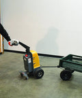 Heavy Duty Electric Powered Tugger With 1000 Lb Pull Capacity For Effortless Factory Material Handling, being operated in a warehouse.