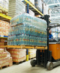 Forklift with orange body lifting a pallet of plastic bottled water in a warehouse