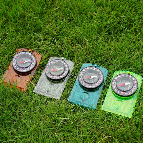 Outdoor Compass Kit With Adjustable Declination, Magnifier, Ruler And Scale in transparent blue green orange on grass