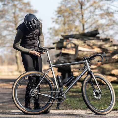 Cyclist adjusting a bike with adjustable 360mm bike cargo straps set for bikepacking, featuring TPU grip for securement on long rides.