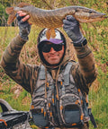 Fishing enthusiast wearing Lightweight Mesh Fishing Vest For Men And Women With 17 Pockets, holding a large fish outdoors.