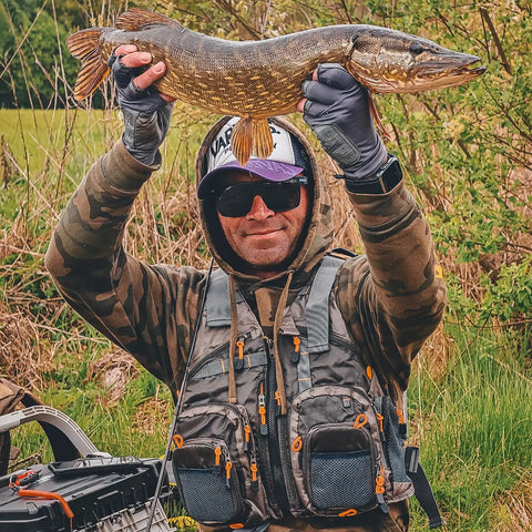 Fishing enthusiast wearing Lightweight Mesh Fishing Vest For Men And Women With 17 Pockets, holding a large fish outdoors.