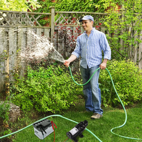 Man using Heavy Duty 12 Volt Dc Diaphragm Water Pump With Hose Clamps For Rv Camper Marine And Utility Work straight shooter design in garden.