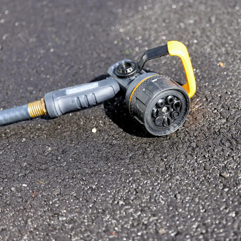 Torrent Firemans Nozzle With Quick Connect Set on asphalt, showing durable metal core and rubber coating. Seven spray patterns visible.