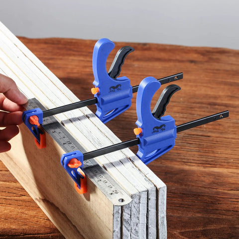 Woodworking Bar Clamps 4 Inch Set of 2 Quick Release One Handed Clamps With Hardened Steel Bar And Soft PVC Pads For Small DIY Projects 65 Lb Clamping Force Blue, clamping wooden boards on a table.