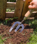 Person using Stainless Steel Hand Fork For Weeding And Planting, Traditional Garden Tool With Ergonomic Ash Wood Handle in soil