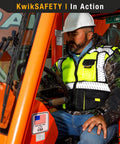 Worker wearing Two Pack High Visibility Safety Vest With Five Pocket Multi Use Design Class 2 ANSI OSHA Reflective Breathable Mesh Heavy Duty Construction Vest For Men Work In Black Large driving forklift