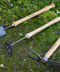 Beefy Dual Function Hand Mattock With Hoe Blade And Grubber For Small Garden Trenching And Root Cutting 15.5 Inch tools on grass.