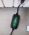 Dead Simple 16 Amp Level One Portable Ev Charger with green LCD screen and connector plugged into an outlet.