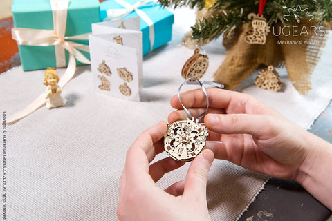 Four In One Wooden Puzzle Kit With Self Assembly Mini Mechanical Models Set Including Stocking Stuffer, Christmas Tree, Clock, And Bauble For Stress Relief, 3D Puzzles Fun For Ages 5 To 80, Plywood Construction, hands holding wooden clock ornament