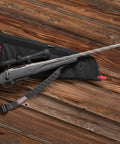 Rifle on a wooden surface with a Baktrak Traction Web Rifle Sling 36 Inch With 500 Pound Swivels, Slim Non Slip Pad attached.