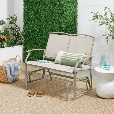 Two Person Outdoor Patio Swing Glider With Smooth Rocking Motion, Textilene Fabric Over Powder Coated Steel Frame in garden setting.