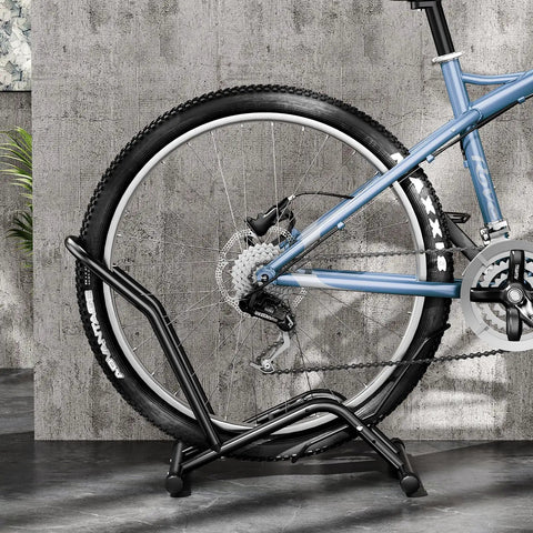Heavy Duty Indoor Bike Floor Stand Adjustable Single Wheel Rack For Garage Ready Setup Fits 16 To 29 Inch Wheels next to a wall