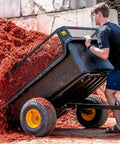 Person unloading Heavy-Duty ATV UTV Utility Trailer With 1500 Lb Capacity, 22 Cu Ft Poly Tub filled with mulch, showing rustproof design.