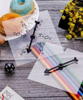 Clear Classroom Spinners 10 Pack With Rotating Arrows For Dry Erase Math Games shown with colored pencils and snacks on a table.