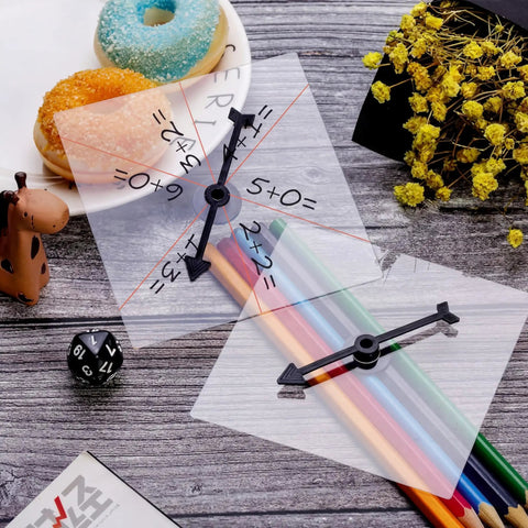 Clear Classroom Spinners 10 Pack With Rotating Arrows For Dry Erase Math Games shown with colored pencils and snacks on a table.