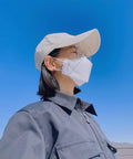 Person wearing Large White KF94 Disposable Mask With 4 Layer Filter And 3D Design, blue sky background, side view