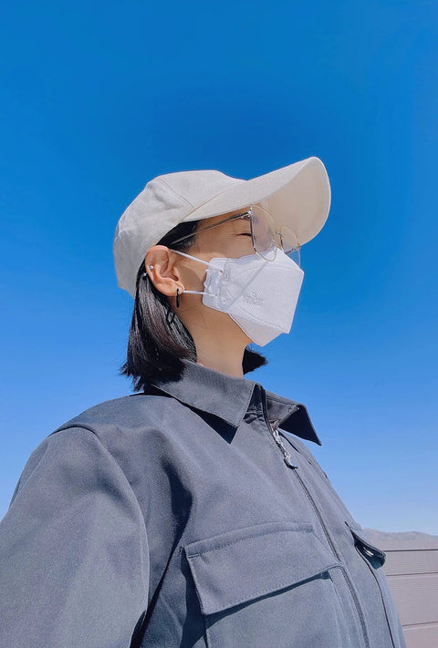 Person wearing Large White KF94 Disposable Mask With 4 Layer Filter And 3D Design, blue sky background, side view
