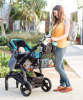Parent using Cups N Cargo Universal Stroller Caddy Organizer with Cup Holders on stroller, carrying baby and essentials.
