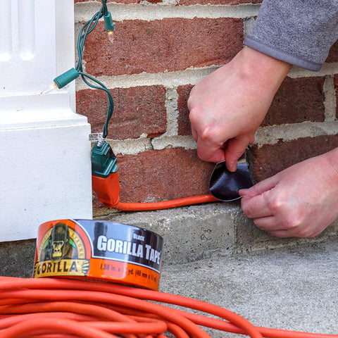 Heavy Duty Black Duct Tape Double Thick Adhesive For Indoor Outdoor Use Grips Rough Surfaces taped to brick wall