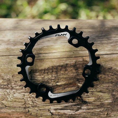 34T Narrow Wide Chainring For 9 To 12 Speed Cranks Asymmetric 96mm BCD Interface Single Ring Upgrade For MTB BMX Gravel Road Bikes Black Durable Alloy Construction For Tough Trails And All Weather Riding on a wooden surface