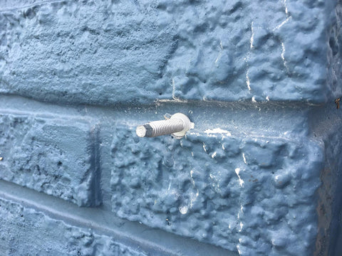 Panelmate Pro Storm Panel Anchors 3-1/4 Inch installed in blue concrete wall for hurricane shutter mounting