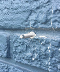 PanelMate Pro Storm Panel Anchors 2-1/4 Inch for One-Time Installation on blue masonry wall, carbon steel, Stalgard coating.