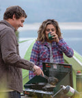 Two Burner Propane Camping Stove With 20,000 BTU Output, Wind Block Panels, And Pressure Regulator For Steady Heat at campsite.