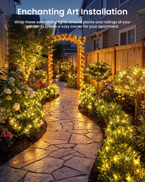 Two Pack 66 Ft Solar Fairy Lights With 200 LEDs In Warm White Outdoor Waterproof String Lights With 8 Modes For Patio Garden Yard Fence Christmas Decor No Fuss Setup And Auto On At Dusk illuminating a garden pathway.