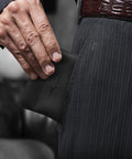 Smooth Vintage Black Leather Squeeze Coin Purse With Heavy Duty Spring Frame being placed into a pocket by a man.