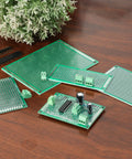 40 Pack Prototyping Printed Circuit Boards Kit With Five Size Universal Perforated Solderable Proto Boards For DIY Electronics Projects Plated Through Holes For Easy Soldering displayed on a wooden surface with electronics components installed.