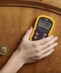 Hand holding Pinless Wood Moisture Meter S300 With Shallow Scan against wood surface