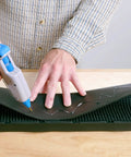 Person using Full Size Hot Glue Gun Kit With 3 Nozzles, 75 Watt Heater, Ergonomic Grip, applying glue to a black surface.