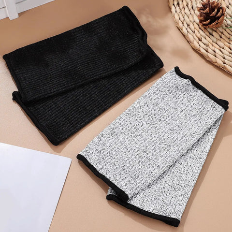 Solid Cut Resistant Forearm Sleeves With A Grippy Nonslip Fit And Thick Reinforced Seaming Built To Dodge Splinters And Scratches On Rough Worksites Or Weekend Garden Projects Reliable Armor That Stays Locked In Wherever You Hustle, featuring black and gray colors on a flat surface.