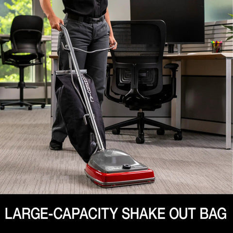 Person using Tradition Upright Commercial Bagged Vacuum Cleaner Workhorse for heavy duty carpet cleaning in office setting.