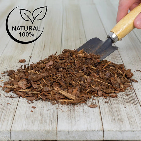 Pile of organic orchid potting bark on wooden surface with a trowel, "One Hundred Percent Organic Orchid Potting Bark Eight Quarts All Natural Pine Bark Mix Additive For Orchids And Epiphytes With Dope Drainage And Airy Roots For Indoor And Outdoor Container Gardening" label visible.