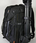 Side view of Large Camera Backpack With Padded Dividers, 16 Inch Laptop Compartment, tripod attached, adjustable straps visible.