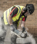 Man using Badass Powered Air Respirator And Hearing Protection Bundle For Woodworking Shops Featuring Full Face Impact Shield Heavy Duty Dust Filters And Integrated Ear Guards Built Tough For Sanding Routing And Turning on a concrete block.