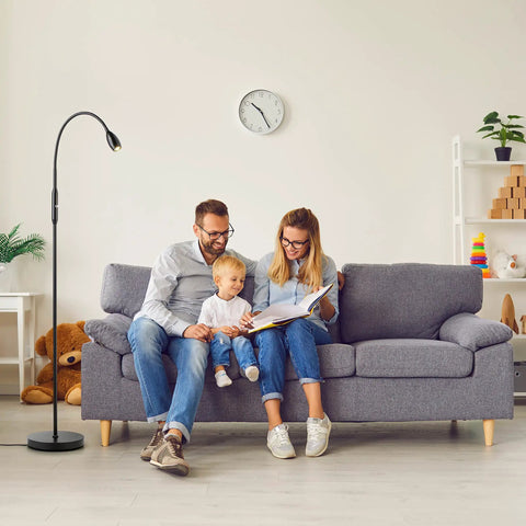 Family reading on sofa beside Adjustable LED Floor Lamp With Dimmable And Zoomable Spotlight, Flexible Gooseneck, Matte Black Standing Lamp