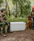 Beast Mode Heavy Duty 120 Qt Polar Cooler With UV Shield Lid in outdoor setting with people in camo and dog.